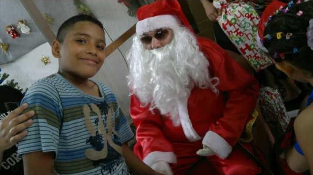 Papai Noel ao lado de um menino na festa de Natal