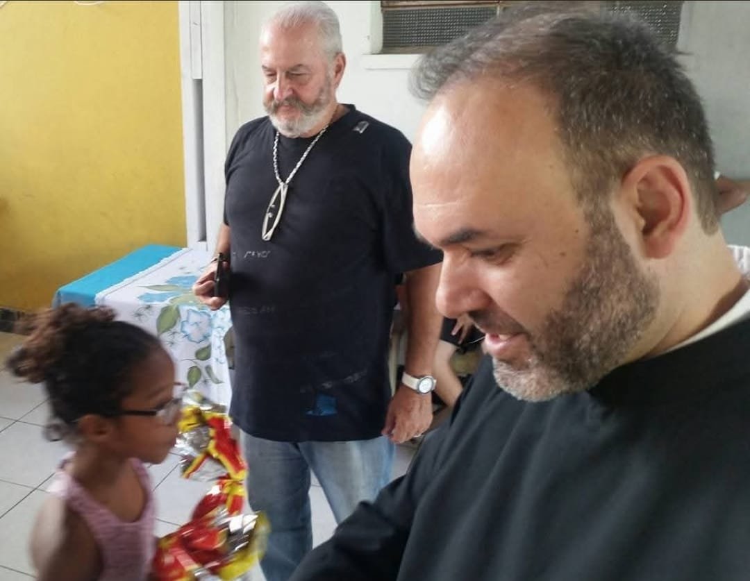 Sacerdote entrega um presente a uma menina