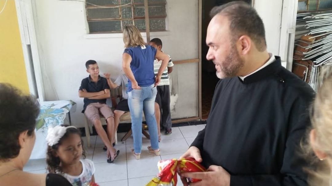 Sacerdote entrega presente a uma criança