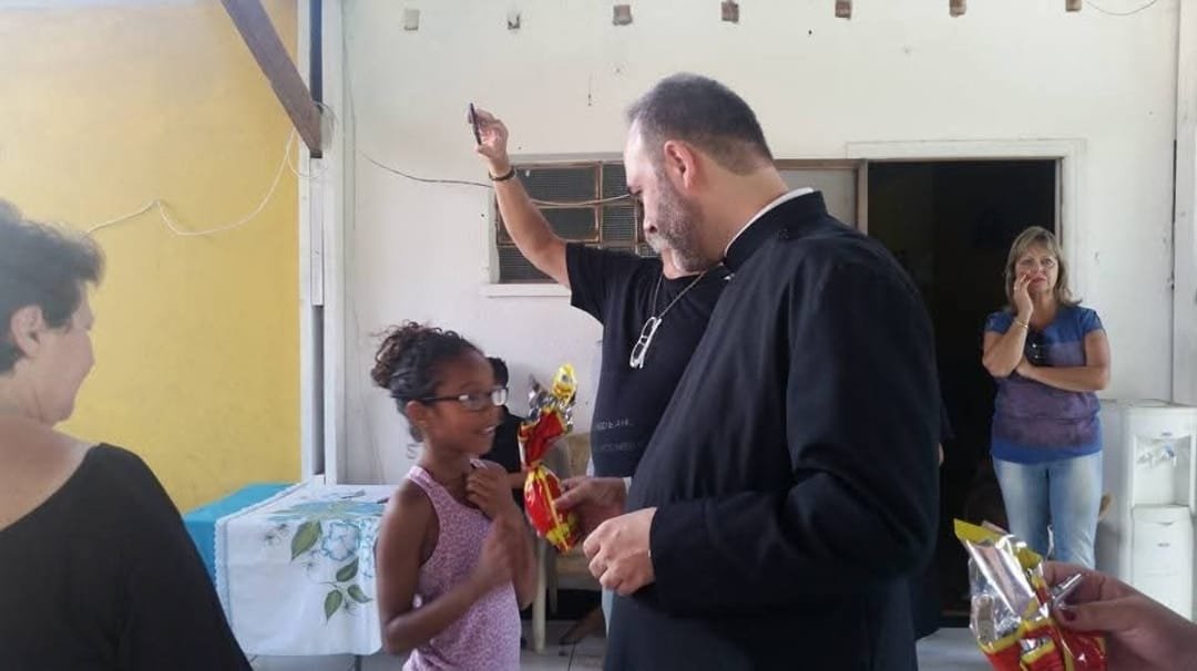 Sacerdote entrega presente a uma menina