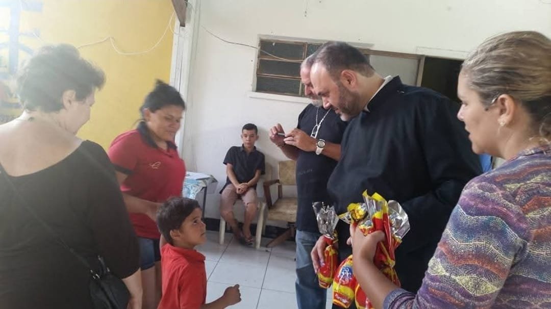 Sacerdote e voluntárias durante a entrega dos presentes