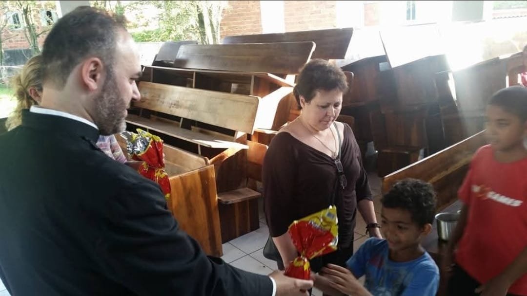Sacerdote entrega presente a um menino
