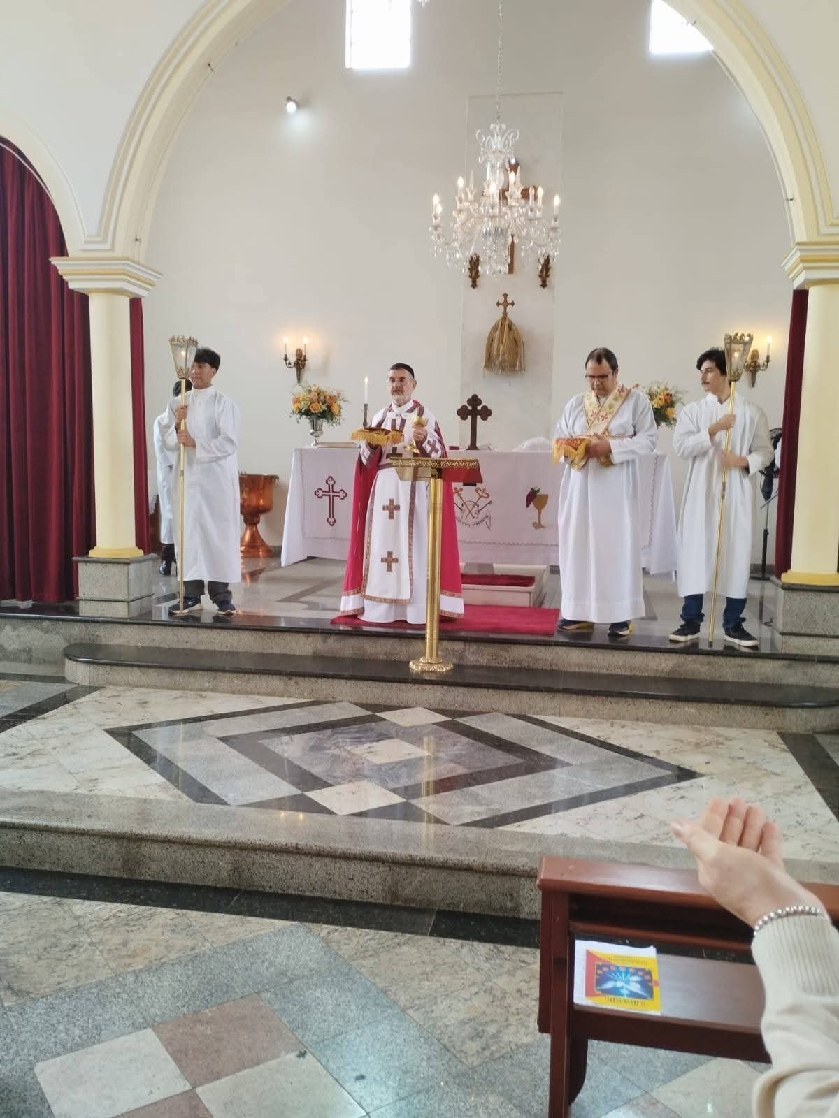Sacerdote no altar com o cálice, acompanhado pelo diácono e pelos acólitos