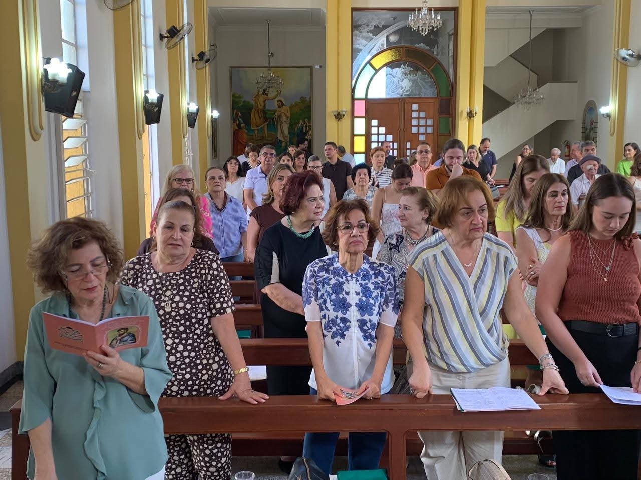 Fiéis de pé acompanhando a celebração